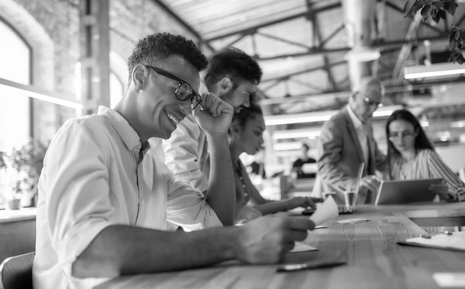 FIVE PEOPLE IN A MEETING AT A TABLE IN AN OFFICE SPACE